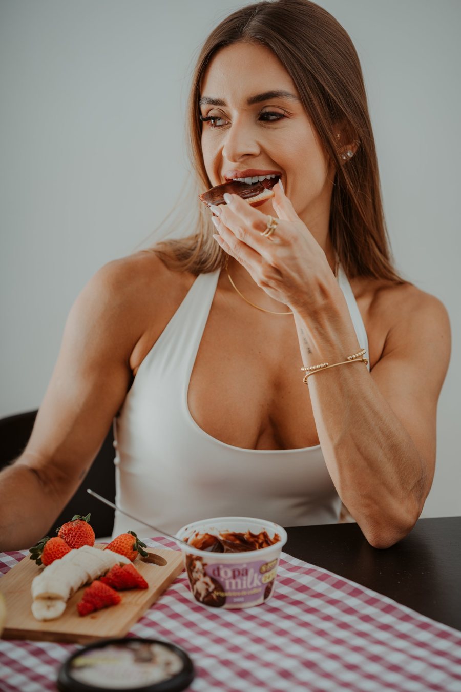 mulher sorrindo enquanto morde um pão com brigadeiro de colher Dopa Milk